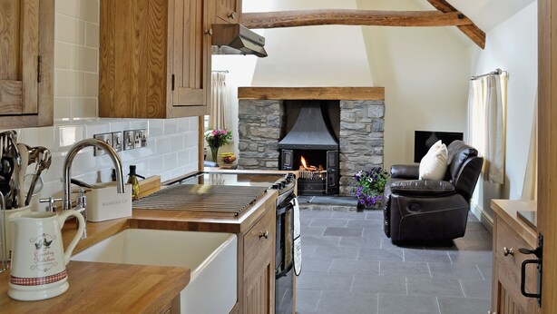 Una cocina con armarios de madera, una chimenea de piedra y un sofá de cuero negro en la sala de estar.