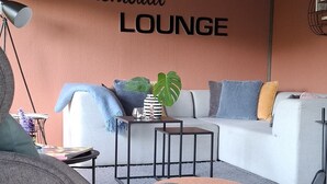 A modern lounge with a sofa, armchair, and ottoman, a coffee table, and a potted plant. - Odenwald Lounge in the Bergstraße-Odenwald Nature Park (Reichelsheim (Odenwald))