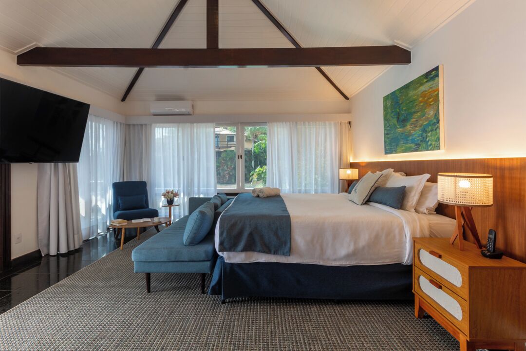 Habitación de hotel con una cama grande, un sofá, un televisor y una ventana con cortinas.
