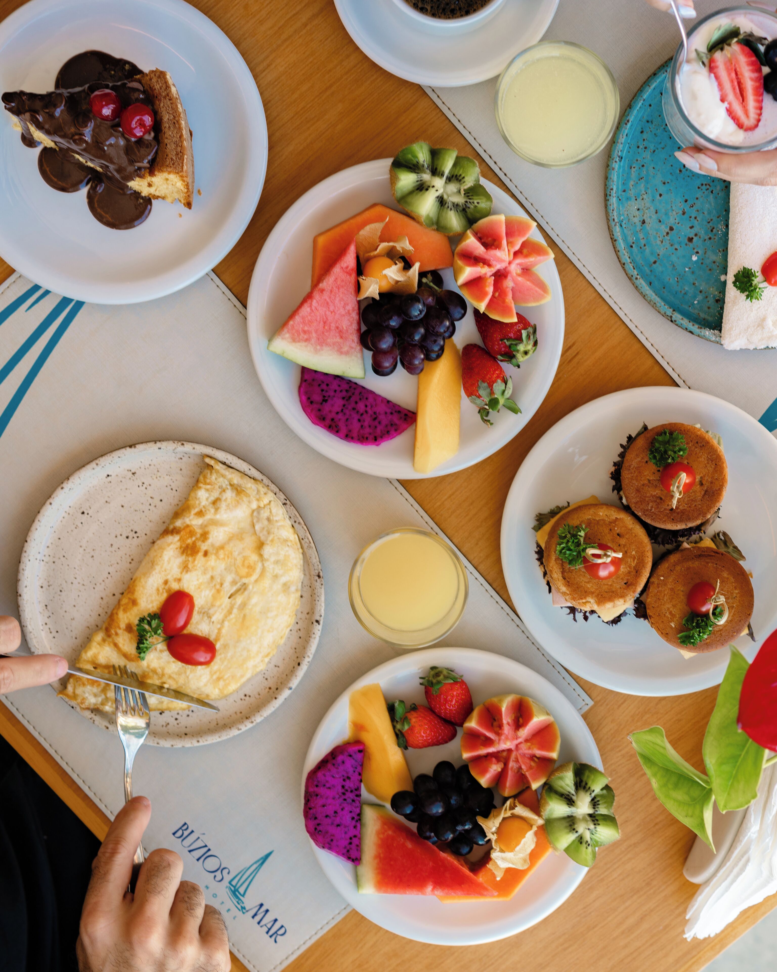 A breakfast buffet with various dishes including fruit, pancakes, and a slice of pie.