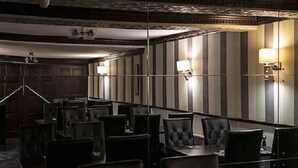 A dimly lit hotel room with a large bed, a bedside table, and a wall-mounted lamp.
