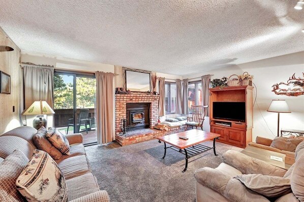A living room with a brick fireplace, a sofa set, a television, and a dining table.