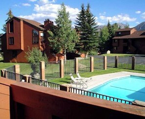 A residential area with a swimming pool, a fenced yard, and houses in the background.