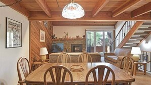 Un intérieur en bois comprenant une table à manger, des chaises, une cheminée et un escalier.