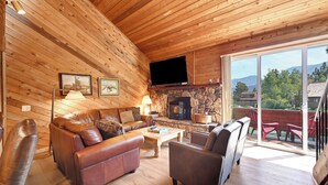 Un interior de madera con chimenea, sofás de cuero y un televisor.