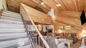 Un interior de madera con una escalera, un sofá de cuero y un comedor.