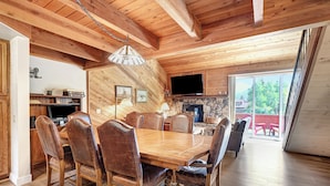 Un interior de madera con comedor, cocina y chimenea.