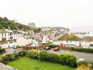 A coastal town with terraced houses, a marina, and a hilly backdrop.