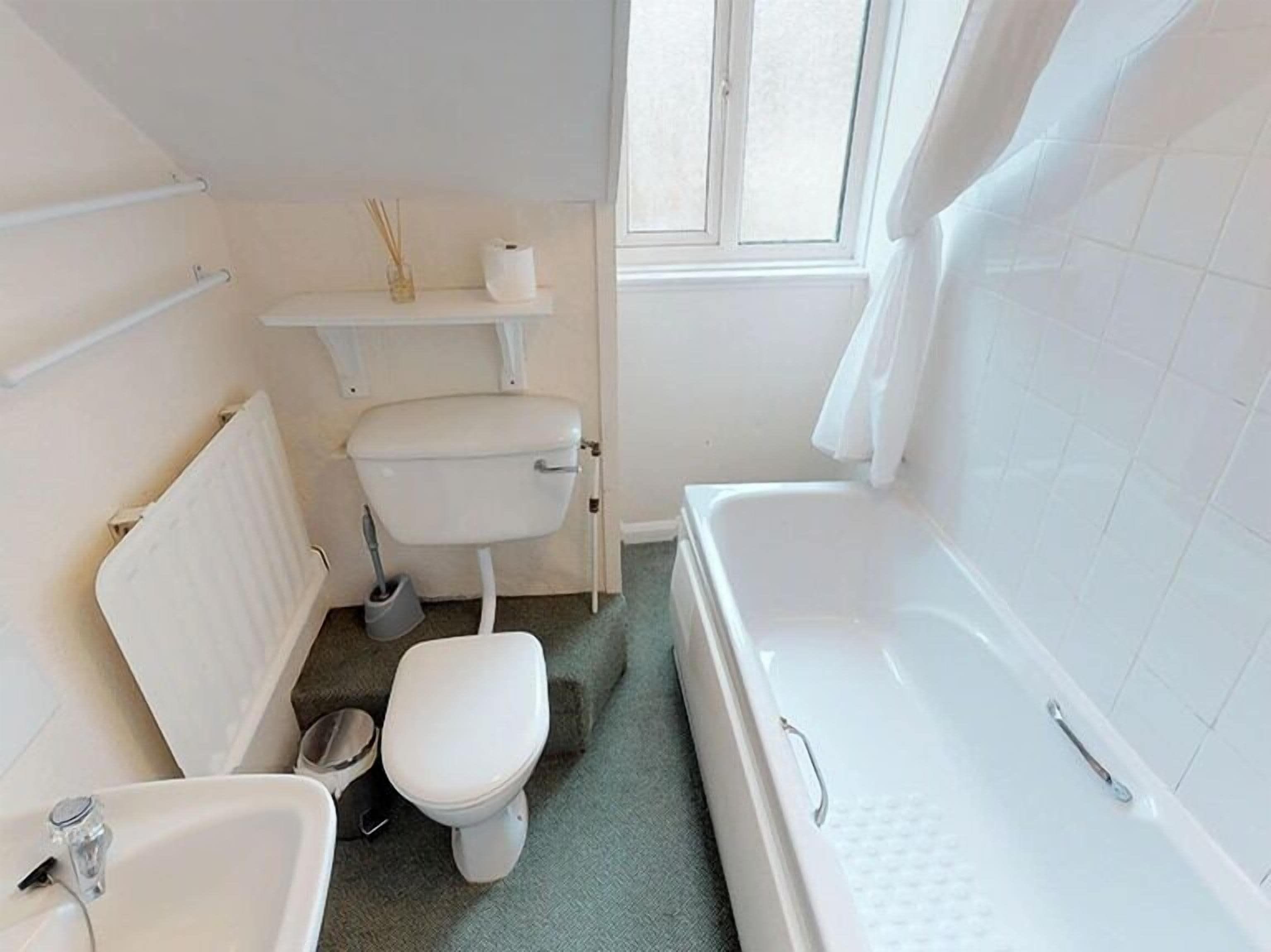 A small, clean bathroom with a toilet, sink, and bathtub.