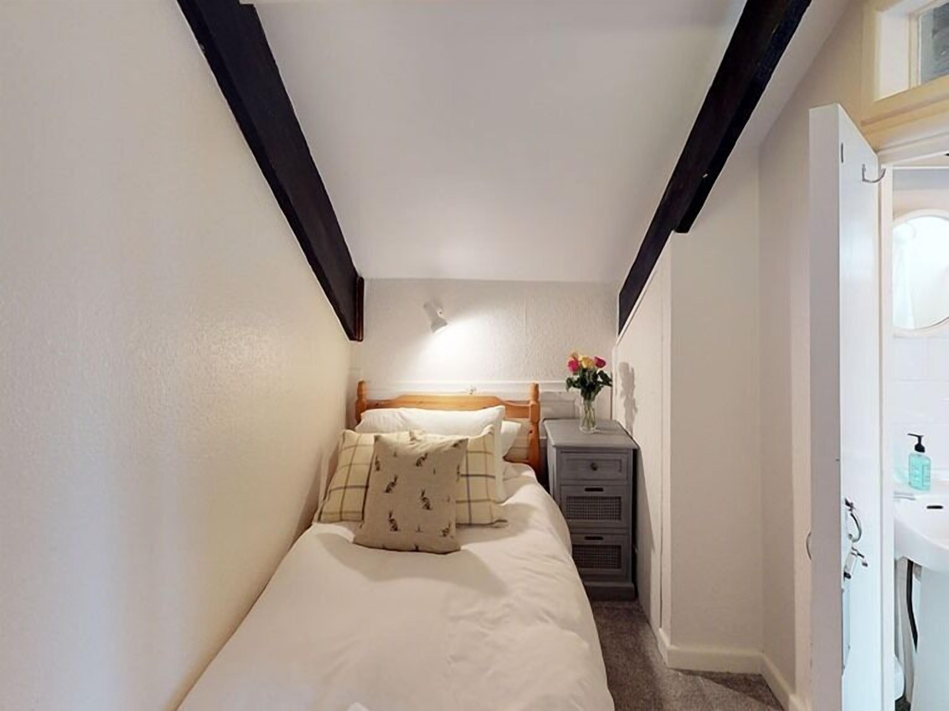 Una habitación pequeña con una cama, un tocador y un escritorio con espejo.