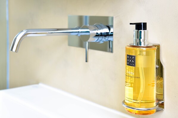 A bathroom with a chrome faucet, a bottle of handwash, and a mirror. - My Story Hotel Augusta (Lisbon)
