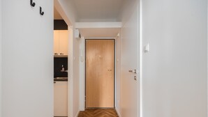 A hallway with a wooden floor leading to a door. - Riverside Comfort Studio (Warsaw)