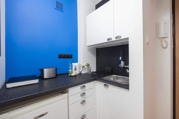 A modern kitchen with white cabinets, a black countertop, and a blue accent wall.