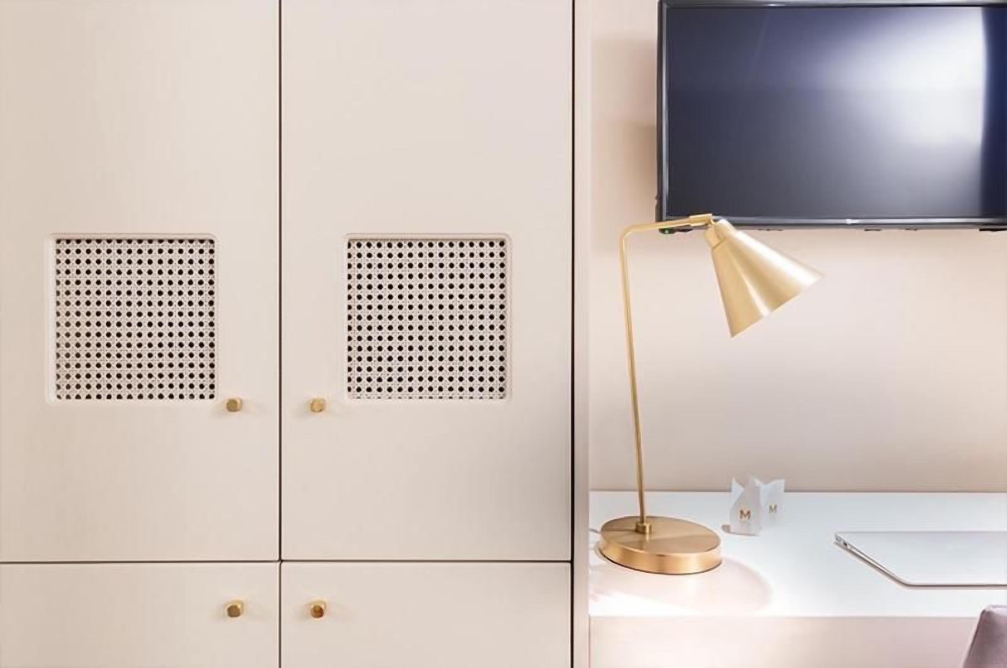 A room with a desk, a lamp, a television, and a wardrobe.