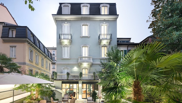 A courtyard with outdoor seating and a building with multiple balconies. - Magville (Milan)