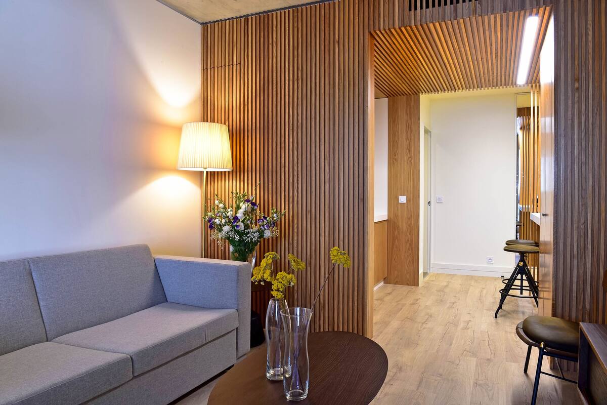Ein modernes Zimmer mit einer Couch, einem Tisch mit Vasen und einer Holzwand.