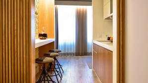 A narrow kitchen with wooden cabinets, a countertop, and three stools. - My Story Apartments Porto - Santa Catarina (Porto)