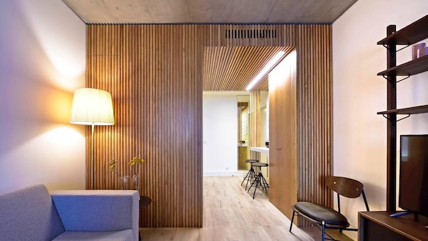 A modern living room with a sofa, a lamp, a TV, and a wooden partition. - My Story Apartments Porto - Santa Catarina (Porto)
