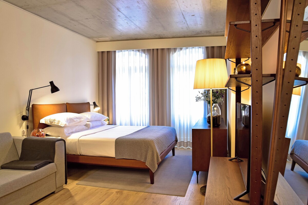 Une chambre d’hôtel avec un lit, un canapé, un bureau et une lampe.