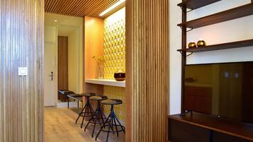 Interior moderno com painéis de madeira, área de bar com banquetas e prateleira com objetos decorativos.