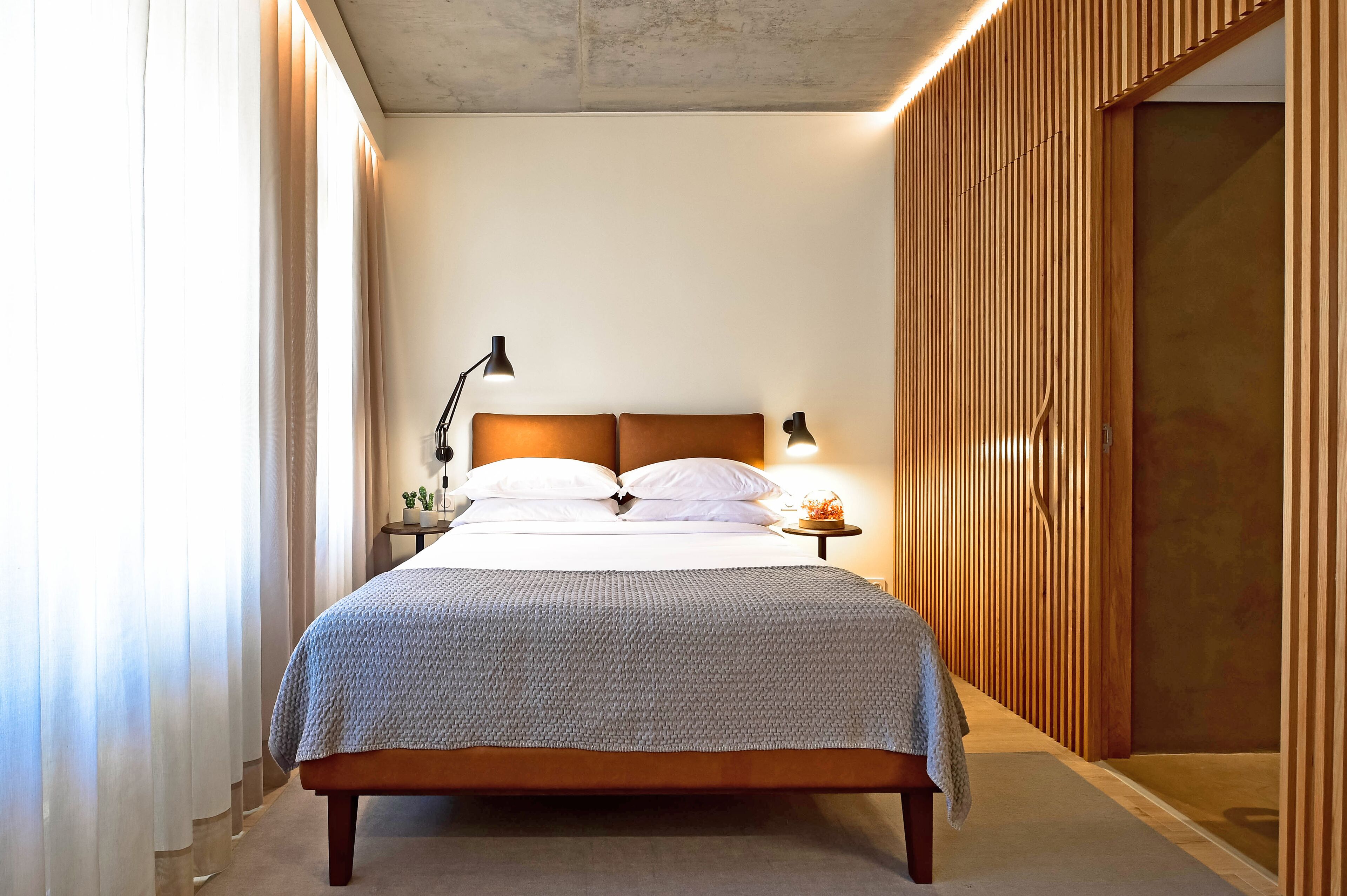 Une chambre à coucher avec une tête de lit en bois, une lampe de chevet et une table de chevet avec une lampe.