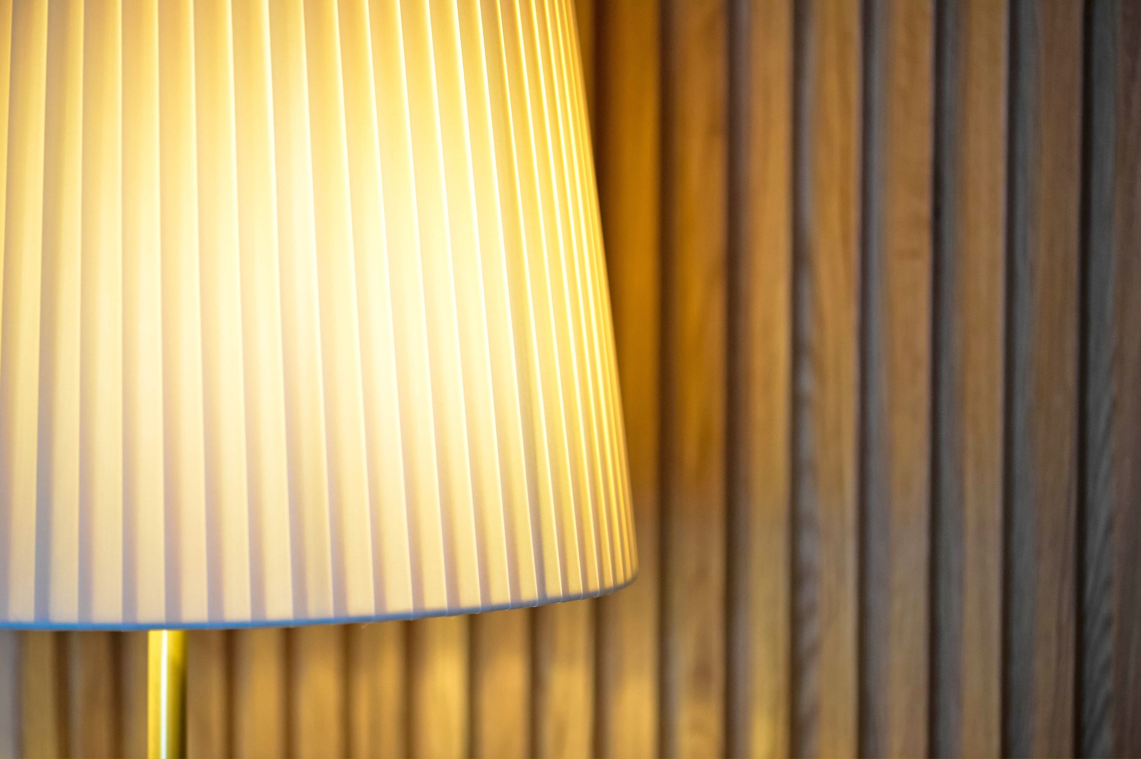 Ein Nahaufnahme einer Lampe mit einer plissierten Schirm vor einem Holzhintergrund.