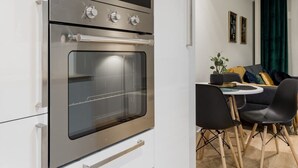 A modern kitchen with a built-in oven and a dining area with a table and chairs. - Mennica Residence Chic Apartment (Warsaw)