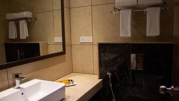 A modern bathroom with a white sink, a mirror, and a black marble shower area.