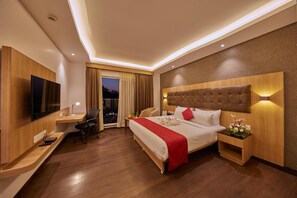 Ein Hotelzimmer mit Bett, Schreibtisch, Fernseher und Blick ins Freie.
