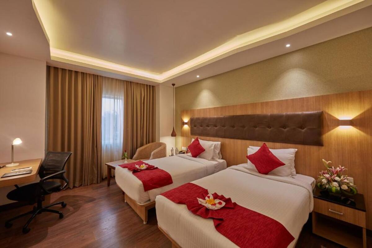 Een hotelkamer met twee bedden, een bureau en een stoel.