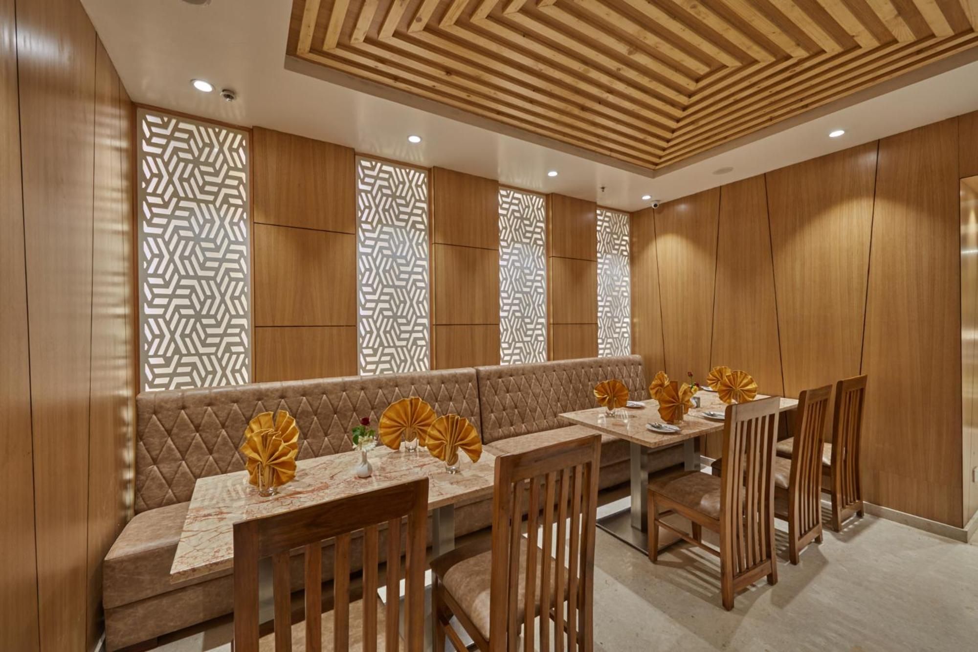 A dining area with a long table, cushioned seating, and patterned wall panels.