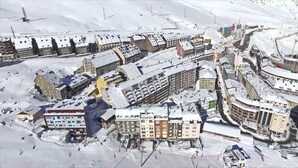 Een besneeuwde stad met verschillende gebouwen, waaronder een hotel en een zichtbare sklift.
