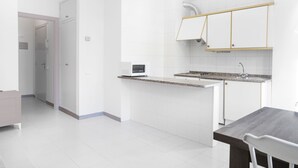 Een moderne keuken met witte kastjes, een granieten aanrechtblad en een inbouwmagnetron.