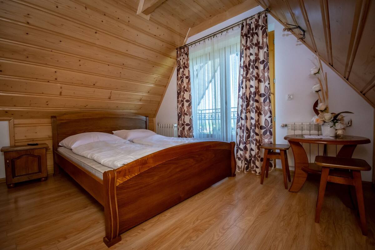 Une chambre à coucher aux murs lambrissés, avec un lit, une petite table et une chaise.