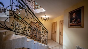 Un escalier orné de rampes en métal ouvragé, un lustre et un tableau accroché au mur.