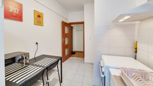 A modern kitchen with a built-in oven, a microwave, and a sink. There is a wooden door leading to another room. - Dream Loft Łagiewniki (Gdansk)