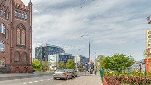 A street with a historic building, modern architecture, and a bus stop. - Dream Loft Łagiewniki (Gdansk)