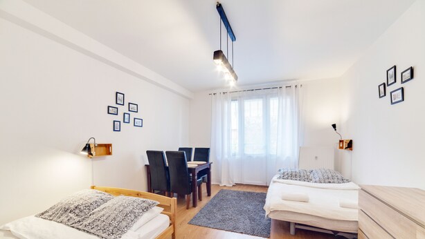 A modern bedroom with two beds, a dining table, and chairs. - Dream Loft Łagiewniki (Gdansk)