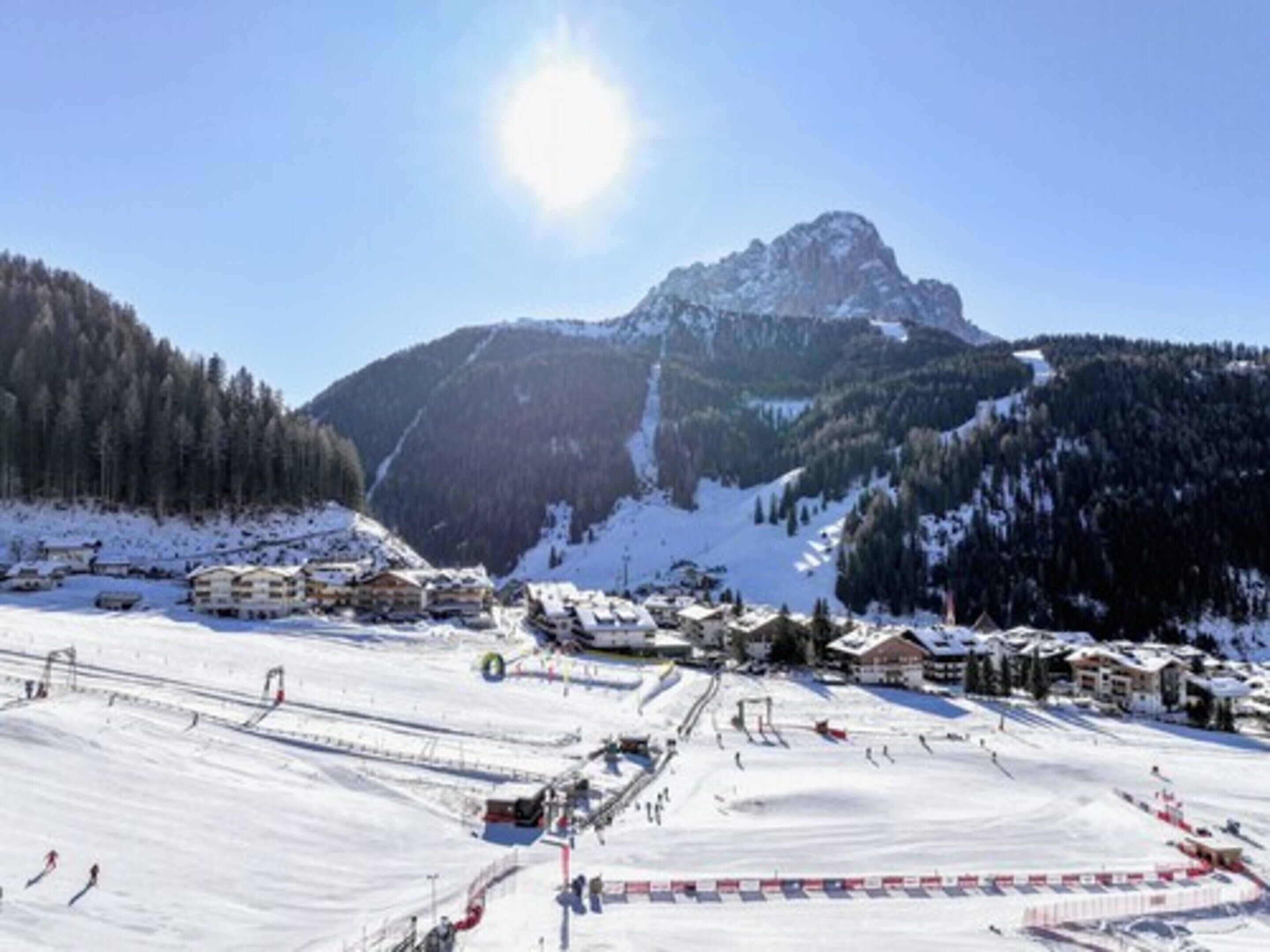 Una stazione sciistica innevata con edifici e una montagna sullo sfondo.