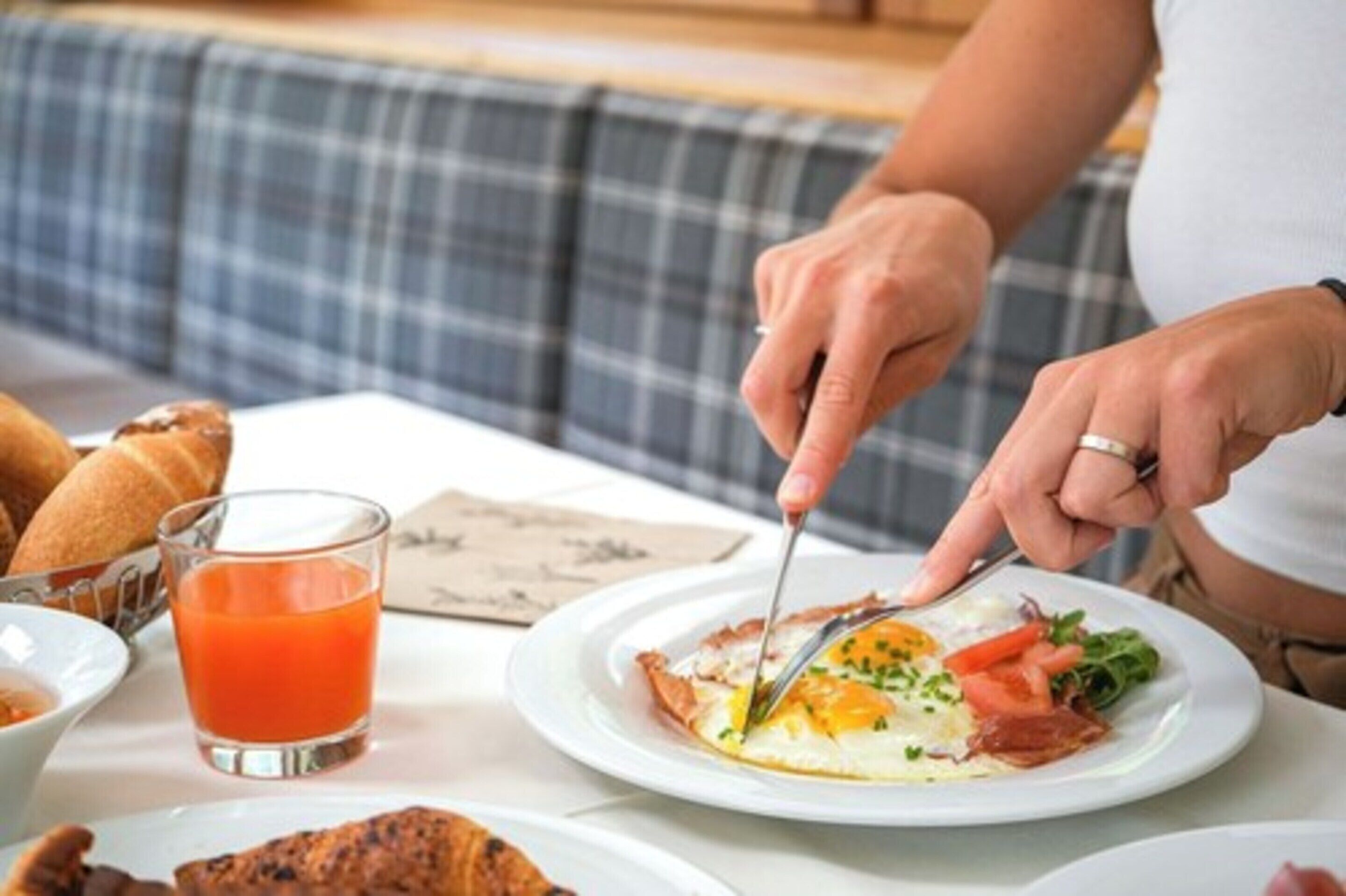 A breakfast setting with a plate of eggs, toast, and a glass of orange juice on a table.
