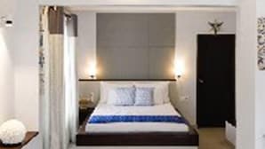 A modern bedroom with a large bed, a nightstand, and a wall-mounted light fixture. - Ayana Beach Resort (Negombo)