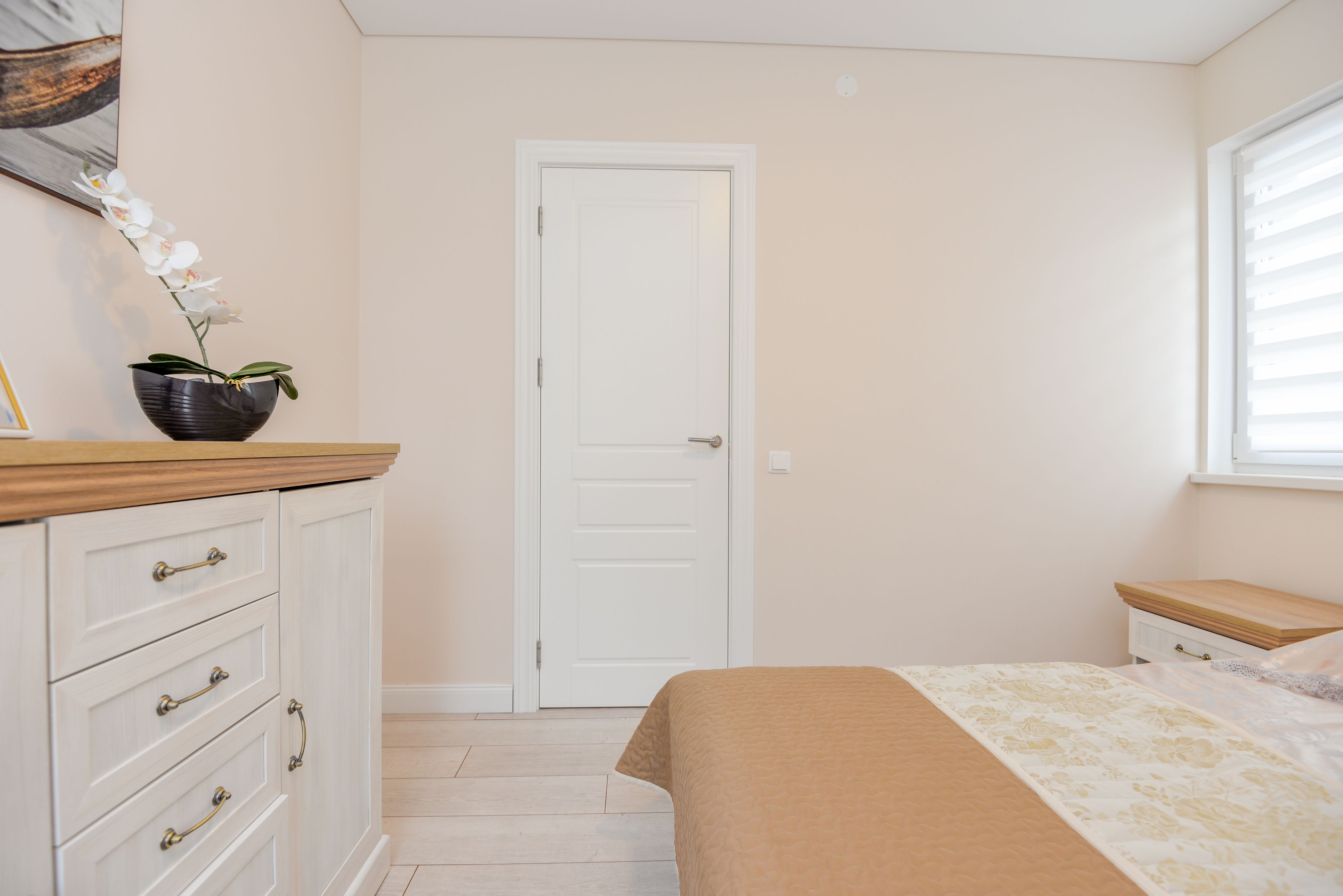 A bedroom with a bed, a dresser, a door, and a window.