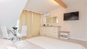 A bedroom with a bed, a TV mounted on the wall, a small table with chairs, and a window with curtains. - Seaside apartments - Near Palanga Beach (Palanga)