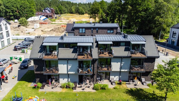 A multi-story residential building with balconies, a parking area, and a playground. - Seaside apartments - Near Palanga Beach (Palanga)