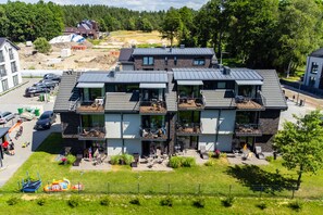 Un immeuble résidentiel à plusieurs étages, doté de balcons, d’un espace de stationnement et d’un terrain de jeux.