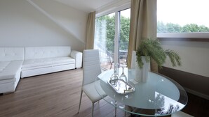 A modern living room with a glass dining table, white sofa, and a large window with curtains. - Seaside apartments - Near Palanga Beach (Palanga)