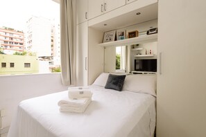 Et hotelværelse med en seng, et vindue og udsigt til bygninger.