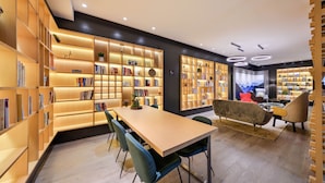 A modern library with wooden bookshelves, a central table, and comfortable seating. - Atour Hotel Hongpailou Chengdu (Chengdu)