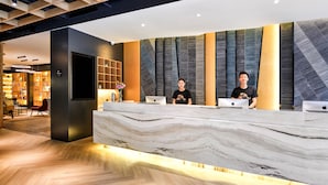 A reception desk with marble top, two staff members, and laptops. - Atour Hotel Hongpailou Chengdu (Chengdu)