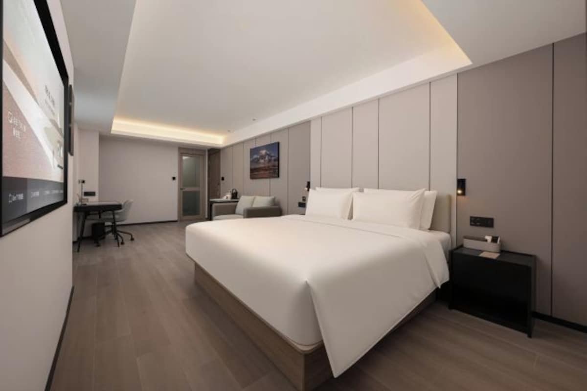 A modern hotel room with a large bed, a desk, and a chair.